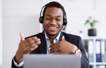 black male wearing headset sitting in front of a laptop