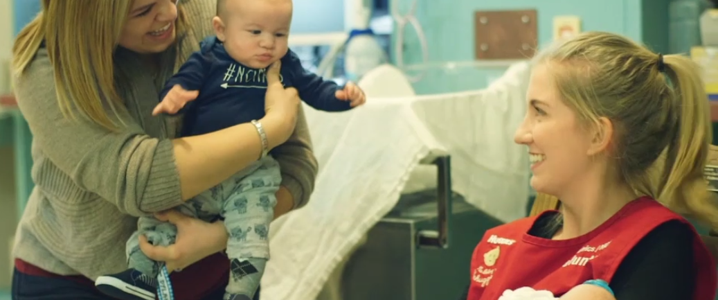 Two smiling women holding babies