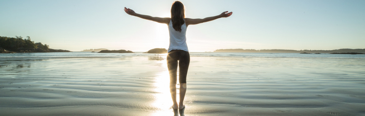 woman with arms outstretched on beach 