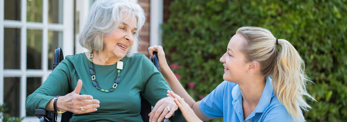 Health care worker talking to senior woman in wheelchair