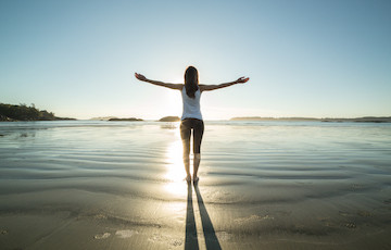 woman with arms outstretched on beach 