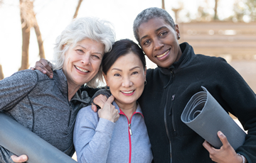 Women hugging holding yoga mats