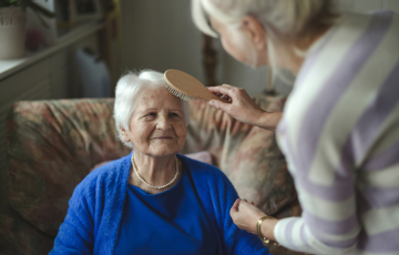 person brushes another person's hair in a home care setting