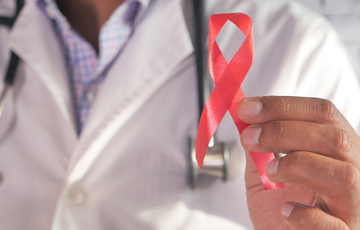 Doctor holding an HIV awareness red ribbon