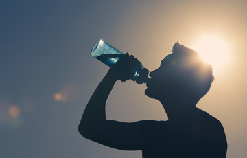 Man drinking water out of a bottle outside