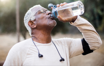 A senior drinking water from a reusable water bottle after exercising