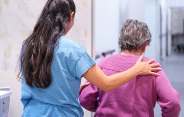 caregiver helping someone walk down hallway