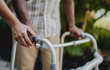 hands on a walker with another hand assisting