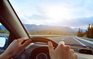 Person driving vehicle with mountain landscape in background