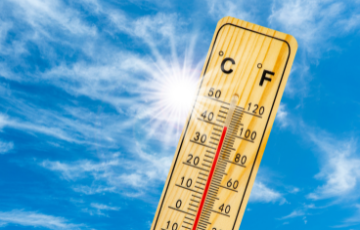 Hot temperature displayed on thermometer with sun in distance