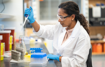 Woman uses pipette to test sample in lab