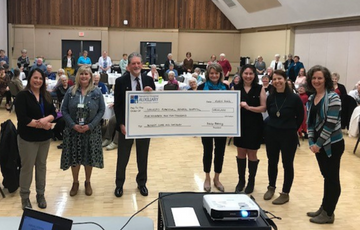 Image of women and men holding a large cheque