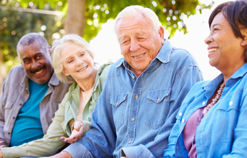 four senior citizens sitting together in a park
