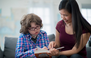 Woman teaching child to read from a book