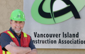 A person standing in front of the Vancouver Island Construction Association