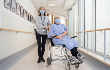 Hospital porter transporting a patient wearing a gown in a hospital hallway