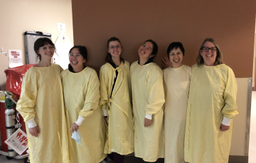 six nurses standing together in medical gowns