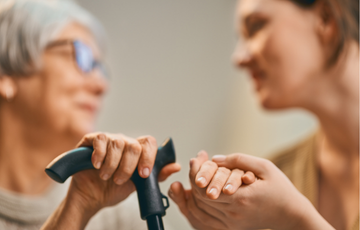two women holding hands one holding a walking device