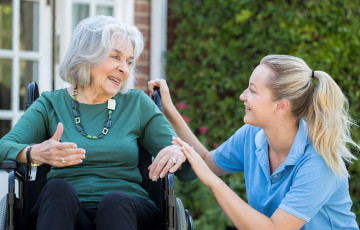 Health care worker talking to senior woman in wheelchair