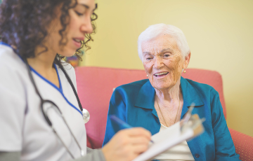 senior woman speaking to a clinician with a clip board