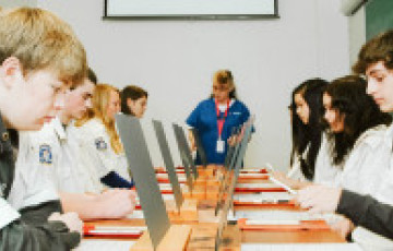 teens learning on computers at a long table